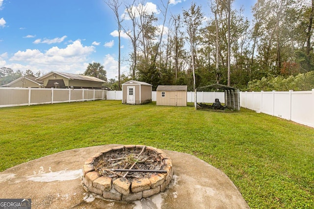 view of yard with an outdoor structure, a fenced backyard, a shed, and an outdoor fire pit