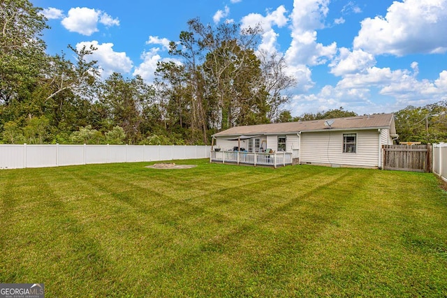 rear view of property featuring a deck, a lawn, and a fenced backyard