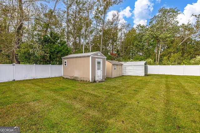 view of yard featuring a storage shed, a fenced backyard, and an outbuilding