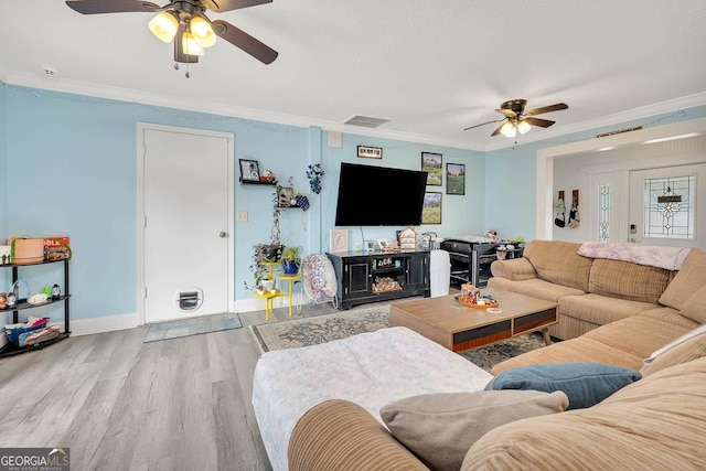 living room featuring a ceiling fan, baseboards, wood finished floors, visible vents, and ornamental molding