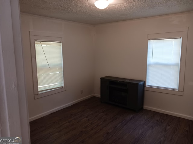 empty room featuring a textured ceiling and dark hardwood / wood-style floors