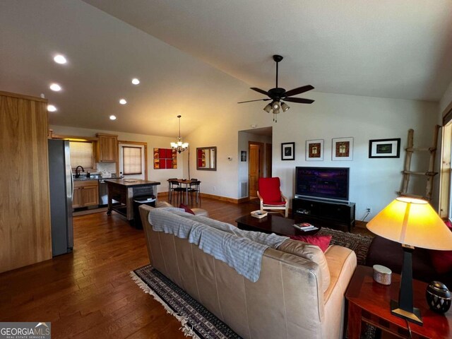 living room featuring ceiling fan with notable chandelier, hardwood / wood-style flooring, sink, and vaulted ceiling