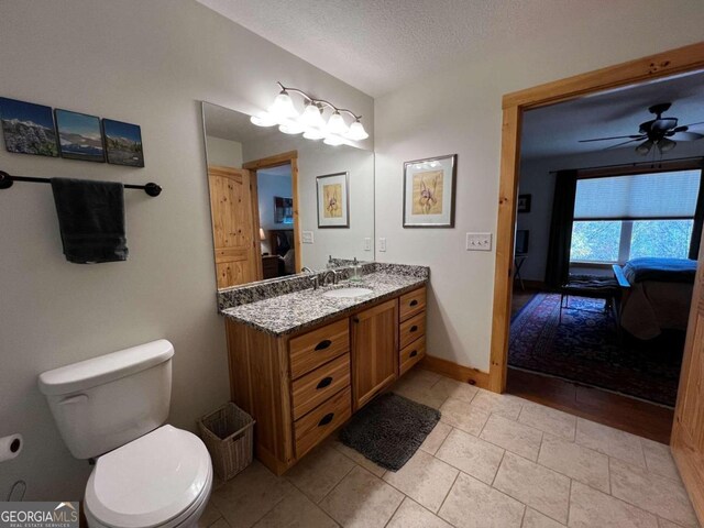 bathroom featuring tile patterned floors, vanity, a textured ceiling, toilet, and ceiling fan