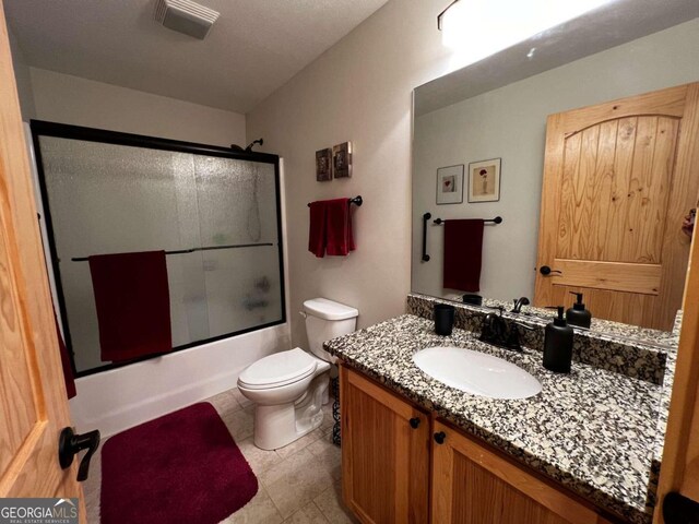 full bathroom featuring toilet, vanity, and shower / bath combination with glass door