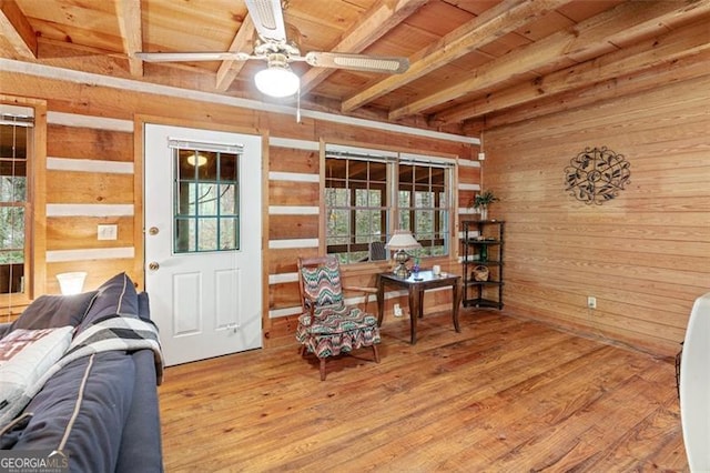 sitting room featuring hardwood / wood-style floors, beamed ceiling, wooden walls, and a healthy amount of sunlight