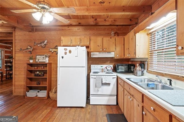 kitchen with wood walls, sink, ceiling fan, light wood-type flooring, and white appliances