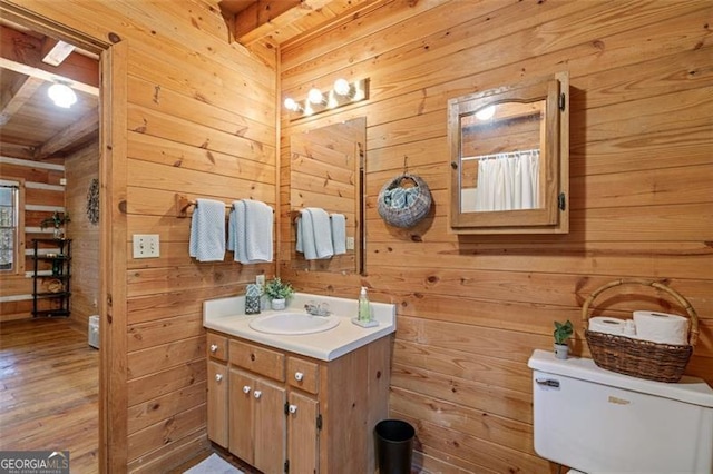 bathroom with wood walls, beamed ceiling, and hardwood / wood-style floors