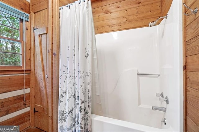 bathroom featuring shower / tub combo with curtain and wood walls