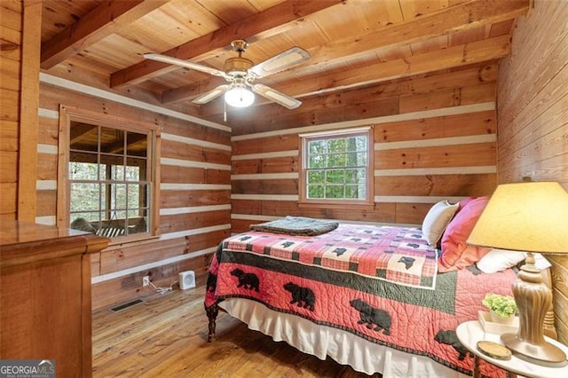 bedroom featuring wooden ceiling, wood walls, ceiling fan, beam ceiling, and hardwood / wood-style floors