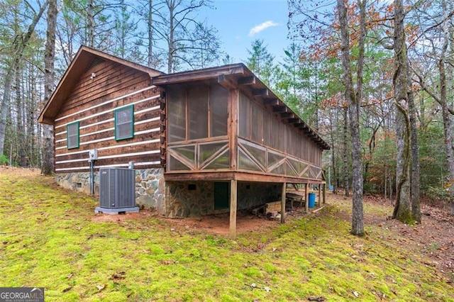 rear view of property with central air condition unit and a sunroom