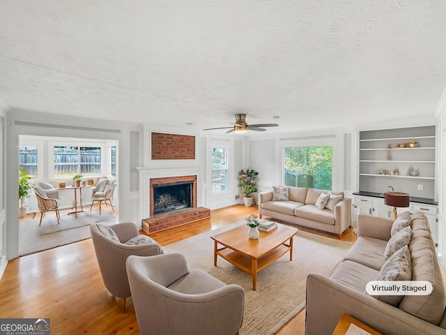 living room featuring a wealth of natural light, ceiling fan, a textured ceiling, and light wood-type flooring