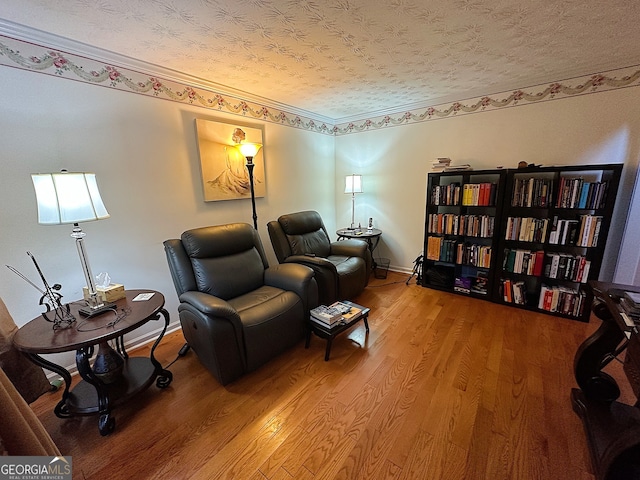 living area featuring hardwood / wood-style flooring, ornamental molding, and a textured ceiling