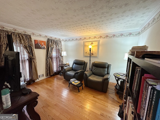 living area featuring a textured ceiling, hardwood / wood-style flooring, and ornamental molding