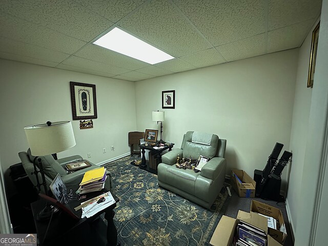 living room featuring a paneled ceiling and carpet