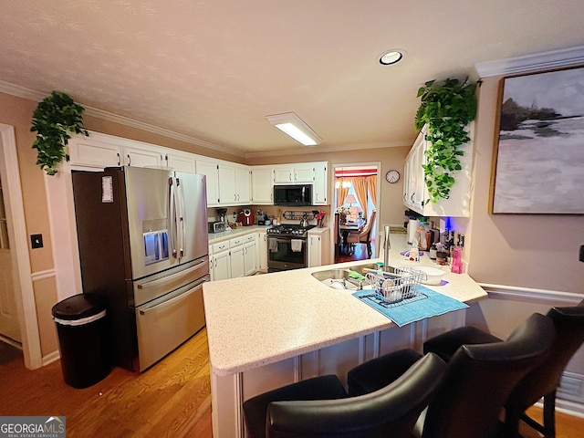 kitchen with white cabinets, appliances with stainless steel finishes, ornamental molding, and light hardwood / wood-style flooring