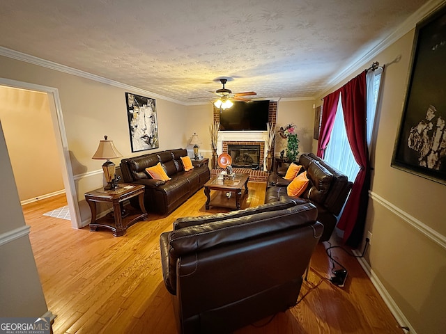 living room featuring ornamental molding, hardwood / wood-style floors, a fireplace, and ceiling fan