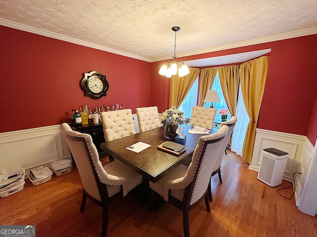 dining room with ornamental molding, hardwood / wood-style floors, a textured ceiling, and a chandelier