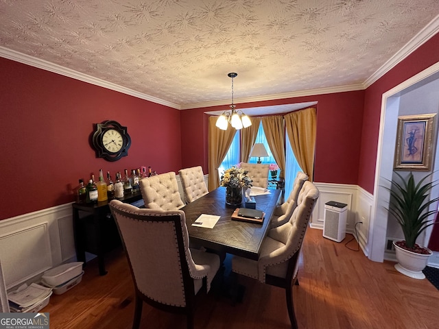 dining space featuring a chandelier, a textured ceiling, dark hardwood / wood-style flooring, and ornamental molding