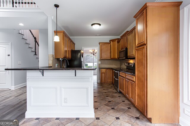 kitchen with decorative backsplash, ornamental molding, a breakfast bar, pendant lighting, and appliances with stainless steel finishes