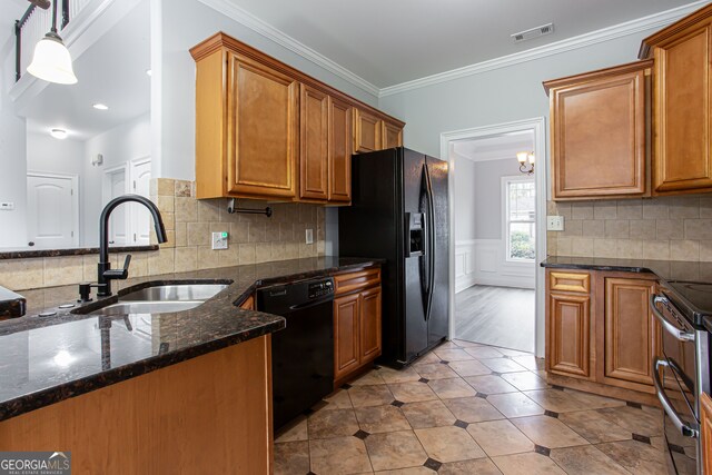 kitchen with black appliances, hanging light fixtures, sink, crown molding, and dark stone countertops