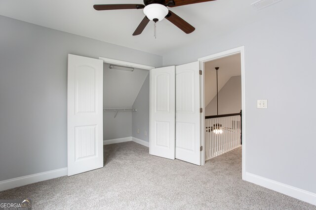 unfurnished bedroom with light colored carpet, ceiling fan, vaulted ceiling, and a closet