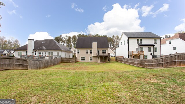 back of house featuring a wooden deck and a lawn