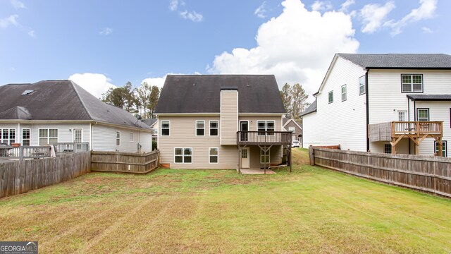 rear view of house featuring a wooden deck and a yard