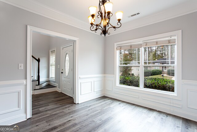 unfurnished dining area featuring hardwood / wood-style flooring, ornamental molding, and a notable chandelier