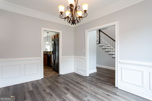 unfurnished dining area with dark wood-type flooring, a chandelier, crown molding, and sink