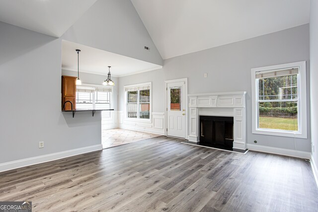 unfurnished living room with light hardwood / wood-style floors, high vaulted ceiling, and a wealth of natural light