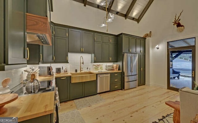 kitchen featuring stainless steel appliances, butcher block counters, green cabinets, high vaulted ceiling, and sink