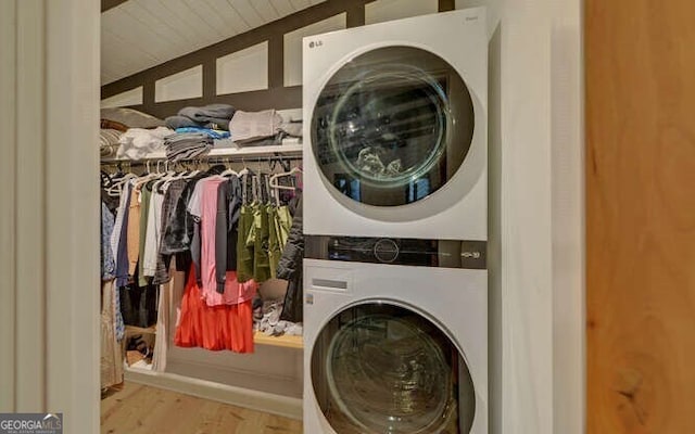 clothes washing area with stacked washer and clothes dryer and light hardwood / wood-style flooring