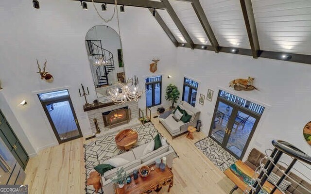 7670 Hiawassee Wilderness Trl, Hiawassee, GA 30546 - living area featuring wood finished floors, a lit fireplace, high vaulted ceiling, beamed ceiling, and french doors