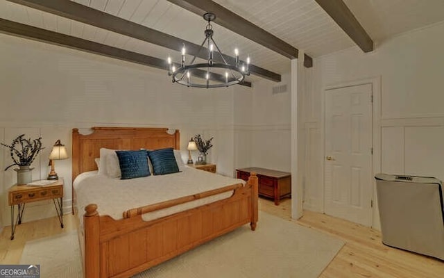 bedroom with light hardwood / wood-style floors, beamed ceiling, and a chandelier