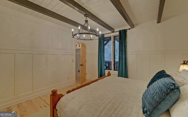 7670 Hiawassee Wilderness Trl, Hiawassee, GA 30546 - bedroom with a decorative wall, beamed ceiling, a chandelier, wainscoting, and wood finished floors