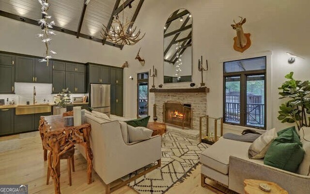 7670 Hiawassee Wilderness Trl, Hiawassee, GA 30546 - living area featuring high vaulted ceiling, beamed ceiling, light wood-style flooring, a chandelier, and a fireplace