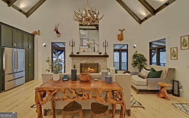 dining area featuring high vaulted ceiling, a fireplace, beamed ceiling, and light wood-type flooring