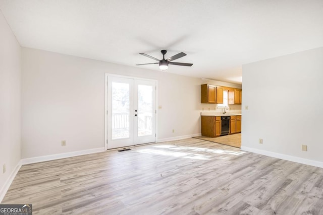 unfurnished living room featuring french doors, light hardwood / wood-style floors, ceiling fan, and sink