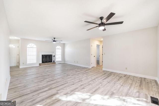 unfurnished living room with ceiling fan, light hardwood / wood-style floors, and a fireplace