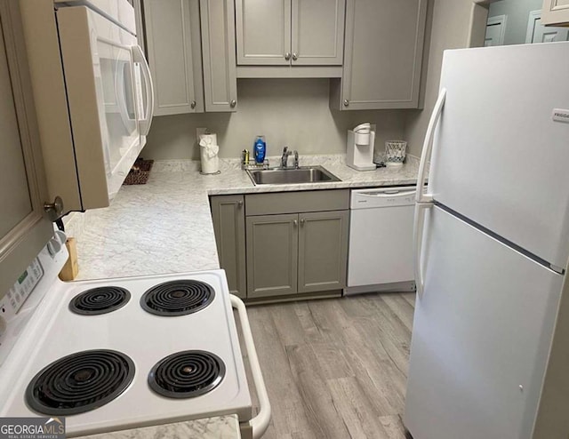 kitchen featuring gray cabinets, white appliances, sink, and light hardwood / wood-style floors