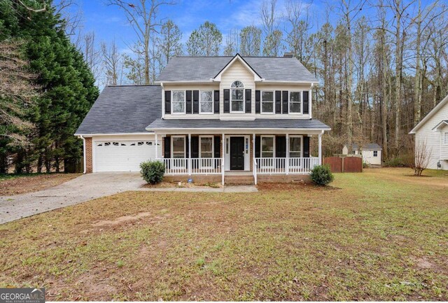 view of front of property featuring covered porch, a garage, and a front yard