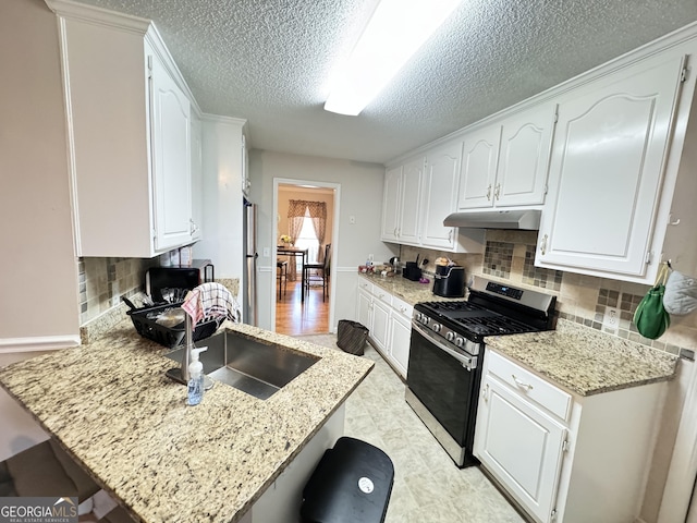 kitchen with white cabinets, decorative backsplash, sink, kitchen peninsula, and stainless steel range with gas stovetop