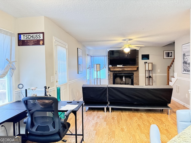 living room featuring hardwood / wood-style flooring, ceiling fan, a textured ceiling, and a fireplace