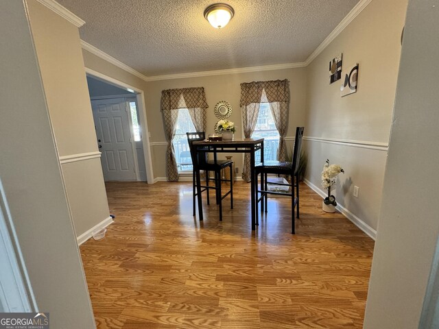 dining room featuring crown molding, wood-type flooring, and a textured ceiling