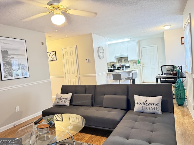 living room with light wood-type flooring, a textured ceiling, and ceiling fan