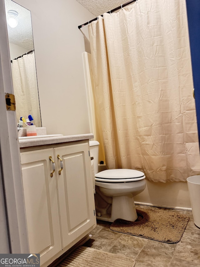 bathroom with a textured ceiling, toilet, and vanity