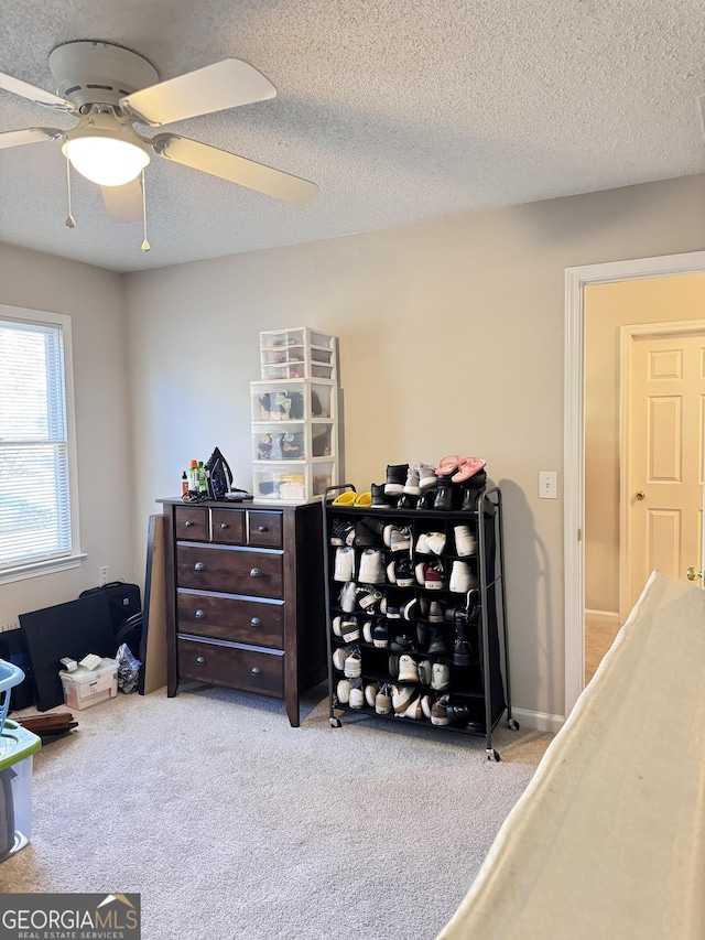 carpeted bedroom with ceiling fan and a textured ceiling