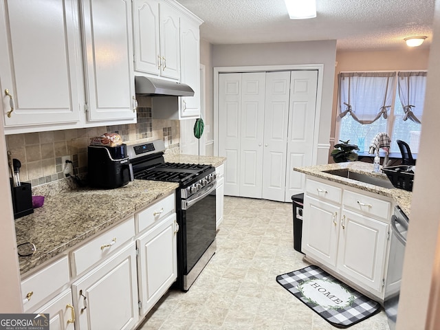 kitchen featuring sink, tasteful backsplash, white cabinetry, light stone countertops, and stainless steel appliances