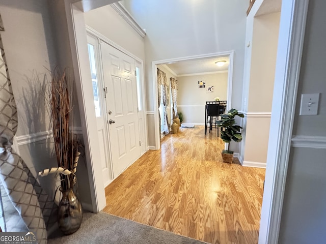 foyer featuring light wood-type flooring, a healthy amount of sunlight, and ornamental molding