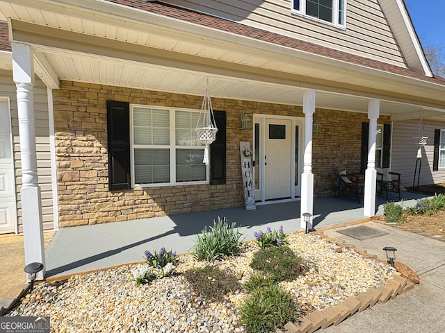 view of exterior entry with stone siding and a porch